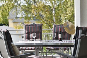 An outdoor patio with a table set for two, featuring striped cushions and a wine bottle. - Holiday apartment with 2 bedrooms (Breege\/Juliusruh OT Juliusruh)
