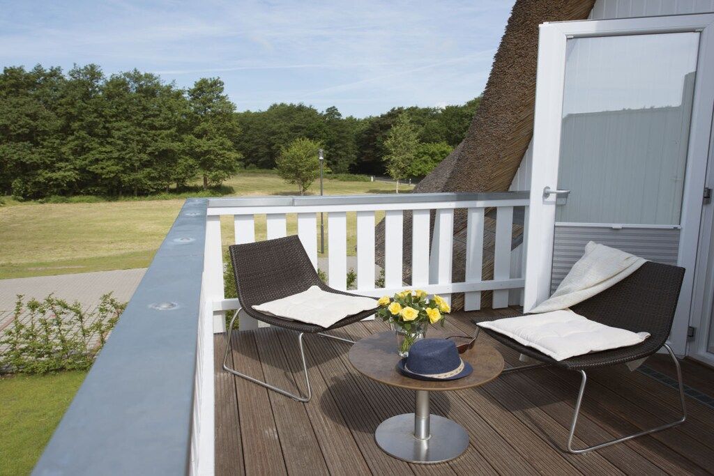 Una terraza con dos sillas, una mesa y un florero.