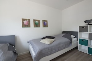 A bedroom with a bed, a nightstand, a wardrobe, and three wall-mounted paintings of animals. - Holiday home in Breege with sauna and Wi-Fi (Breege)