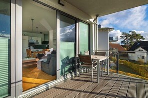 Un balcon avec un plancher en bois, une table et des chaises.