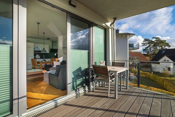Ein Balkon mit Holzboden, einem Tisch und Stühlen.