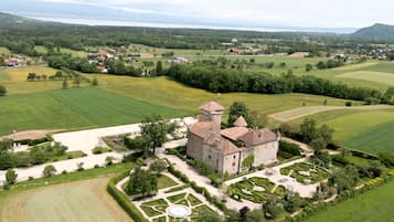 Un castillo con una torre, rodeado de jardines cuidados y campos.