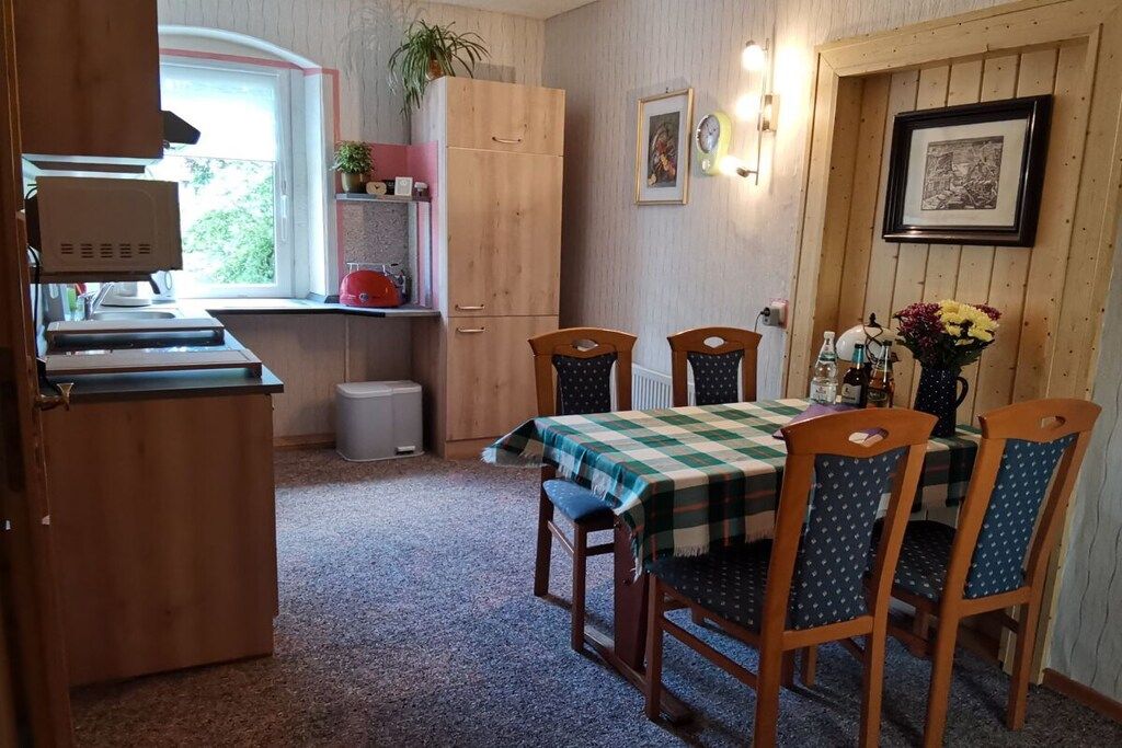 Cocina compacta con comedor, armarios de madera, un radiador y una ventana con vistas.