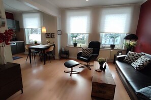 A modern living space with a dining area, a sofa, and a kitchen in the background. - Holiday apartment in Lübeck with barbecue (Lübeck)