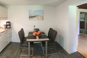 Ein Essbereich mit Tisch und Stühlen, einer Kaffeemaschine und einem Bild an der Wand.