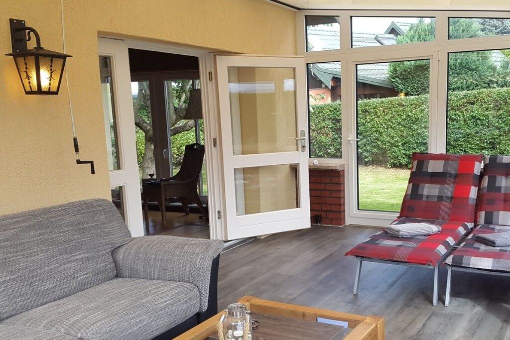 A room with a sofa, a table with a glass container, and a red and grey plaid sofa.