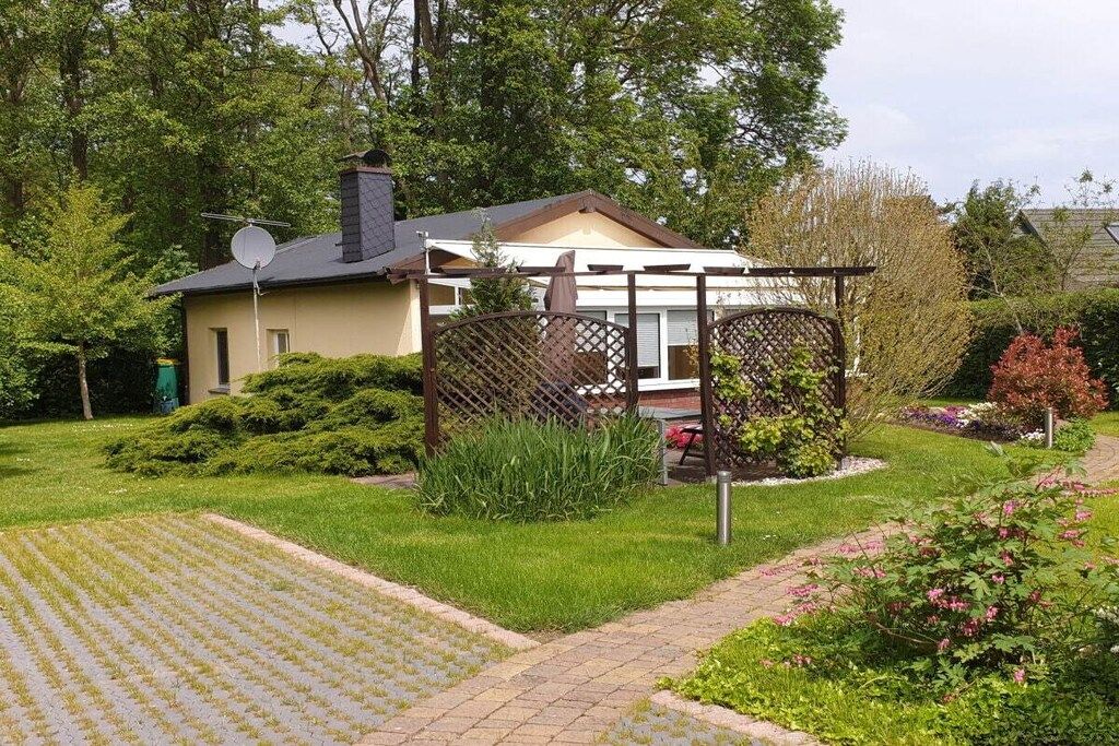 Een woonhuis met een verharde oprit, een omheind gazon en een huis met schoorsteen.