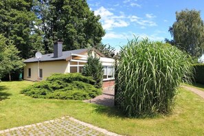 Ein Wohnhaus mit befestigter Auffahrt, einem gepflegten Rasen und einem großen Busch.