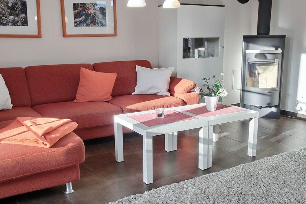 A modern living room with a red sofa, white coffee table, and a fireplace.