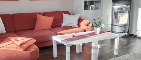 Una sala de estar moderna con un sofá rojo, una mesa de centro blanca y una chimenea.