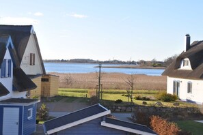 A residential area with houses near a body of water, featuring a stone wall and a grassy field. - Holiday home with 3 bedrooms (Breege\/ Juliusruh OT Breege)