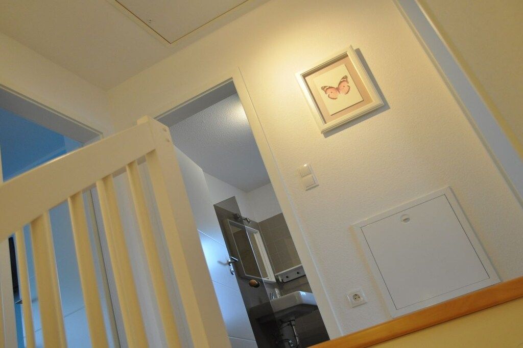 Una escalera que lleva a una habitación con un cuadro en la pared, una puerta y un interruptor de luz.