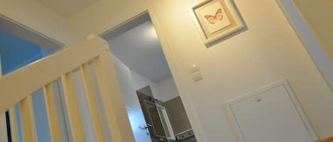 Una escalera que lleva a una habitación con un cuadro en la pared, una puerta y un interruptor de luz.