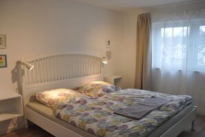 A bedroom with a bed, bedside tables, and a window with curtains. - Holiday home with 3 bedrooms (Breege\/ Juliusruh OT Breege)
