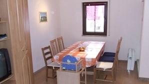 Ein Essbereich mit Tisch, Stühlen, einem Fernseher und einem Fenster.
