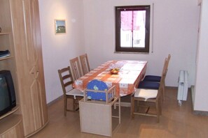 Un comedor con una mesa, sillas, un televisor y una ventana.