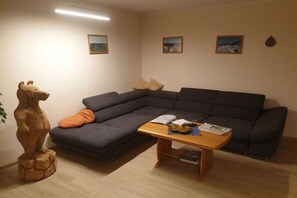 Una sala de estar con un sofá modular, una mesa de centro de madera y una estatua de un oso.