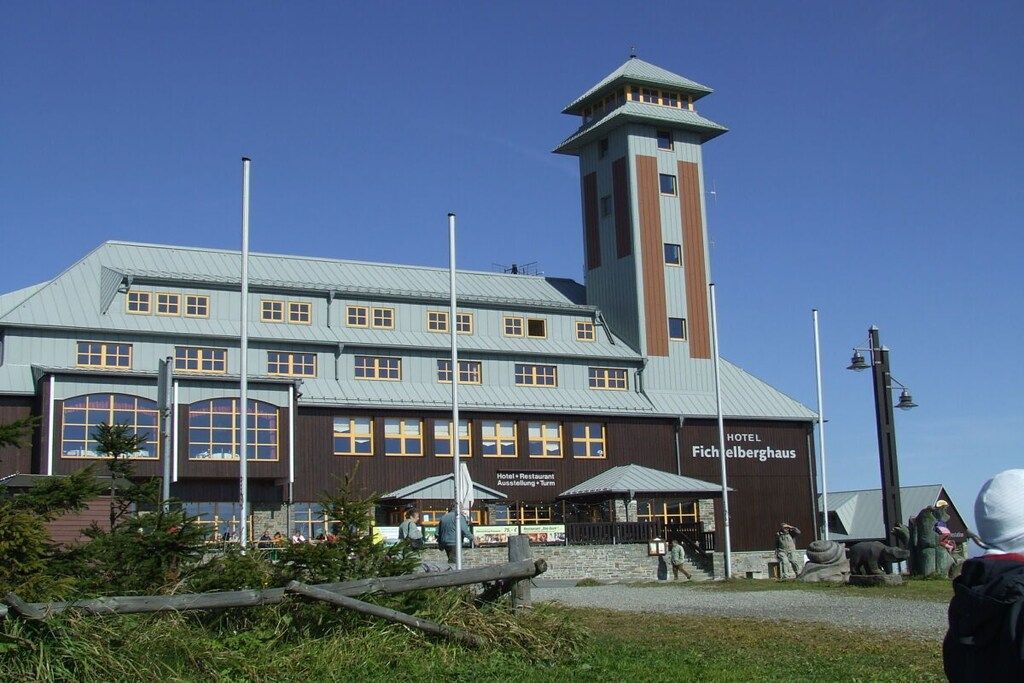 Ein Hotel mit einem markanten Turm, zahlreichen Fenstern und Außenbereichen zum Sitzen.