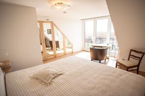A bedroom with a large bed, a chair, a desk, and a view of the outdoors. - Holiday apartment with 2 bedrooms (Breege\/ Juliusruh OT Breege)