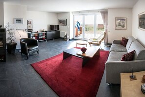 A modern living room with a sofa, armchairs, a coffee table, and a red rug. - Holiday apartment with 2 bedrooms (Breege\/ Juliusruh OT Breege)