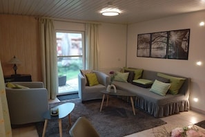 Ein Wohnzimmer mit einer Couch, Sesseln, einem Couchtisch und einer Lampe.