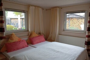 Ein Schlafzimmer mit einem Bett, zwei Fenstern und Vorhängen.