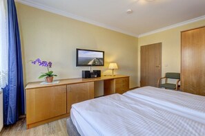 A hotel room with a bed, a desk with a TV, a lamp, and a chair. - At Schloonsee, Apartment C-5 (Seebad Heringsdorf)