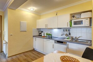 A compact kitchen with white cabinets, a microwave, and a sink. - At Schloonsee, Apartment C-5 (Seebad Heringsdorf)