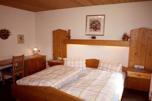 Een slaapkamer met een houten bed, een bureau en een stoel.