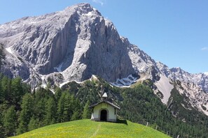 Een berglandschap met een klein kapelletje op de voorgrond en een grote berg op de achtergrond.