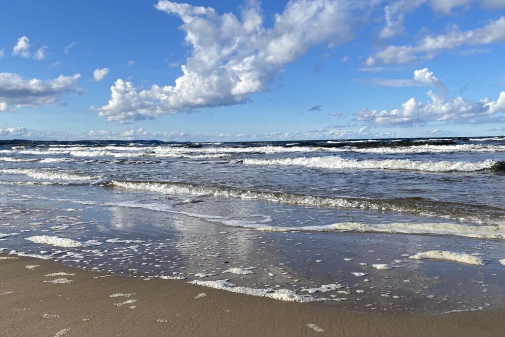 A beach with waves and a clear sky.