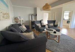 Ein modernes Wohnzimmer mit einer Couch, Sesseln und einem Couchtisch.