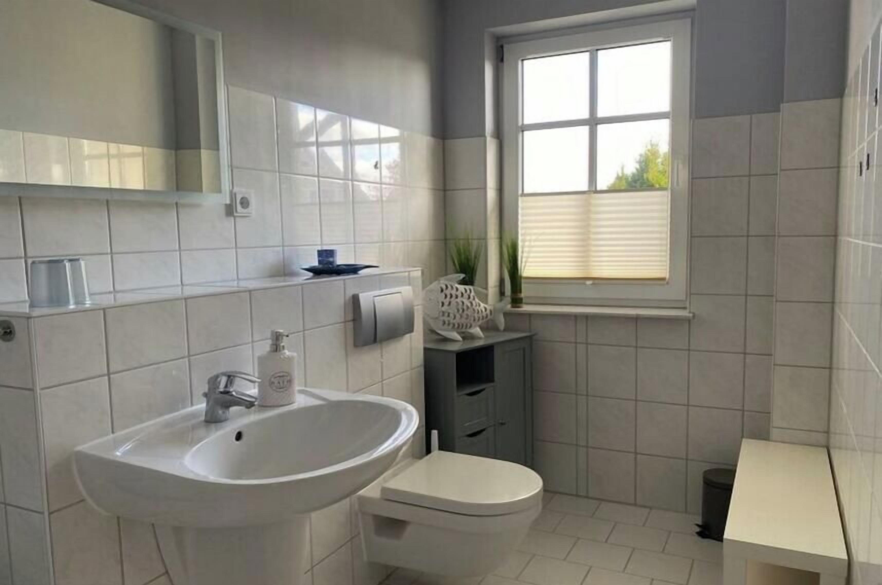 A bathroom with a sink, toilet, and window.