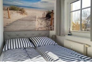 A bedroom with a bed, a window, and a beach mural on the wall. - Holiday apartment with 2 bedrooms (Loddin OT Kölpinsee)