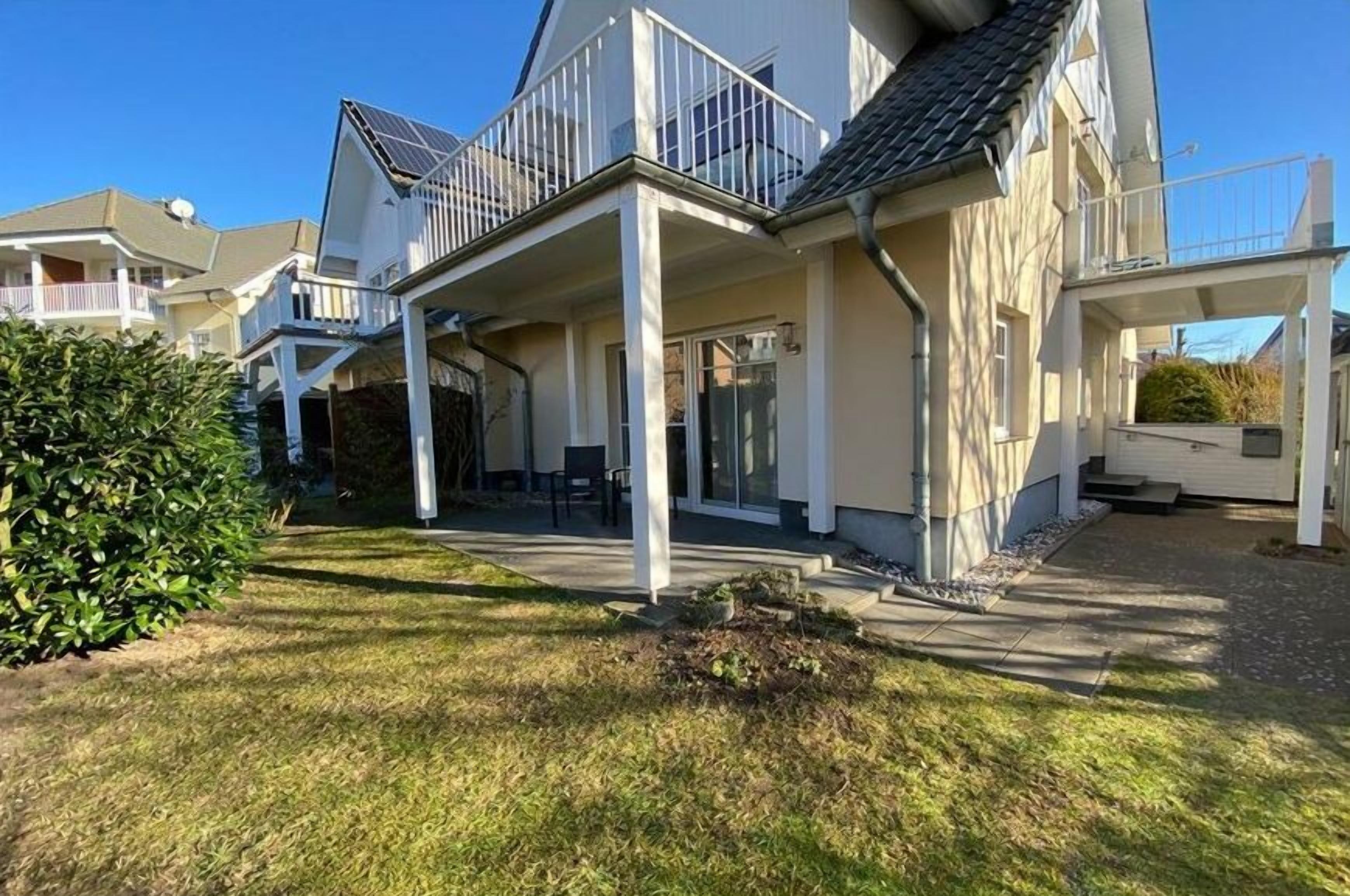A residential building with a covered porch, a small garden, and a clear sky.