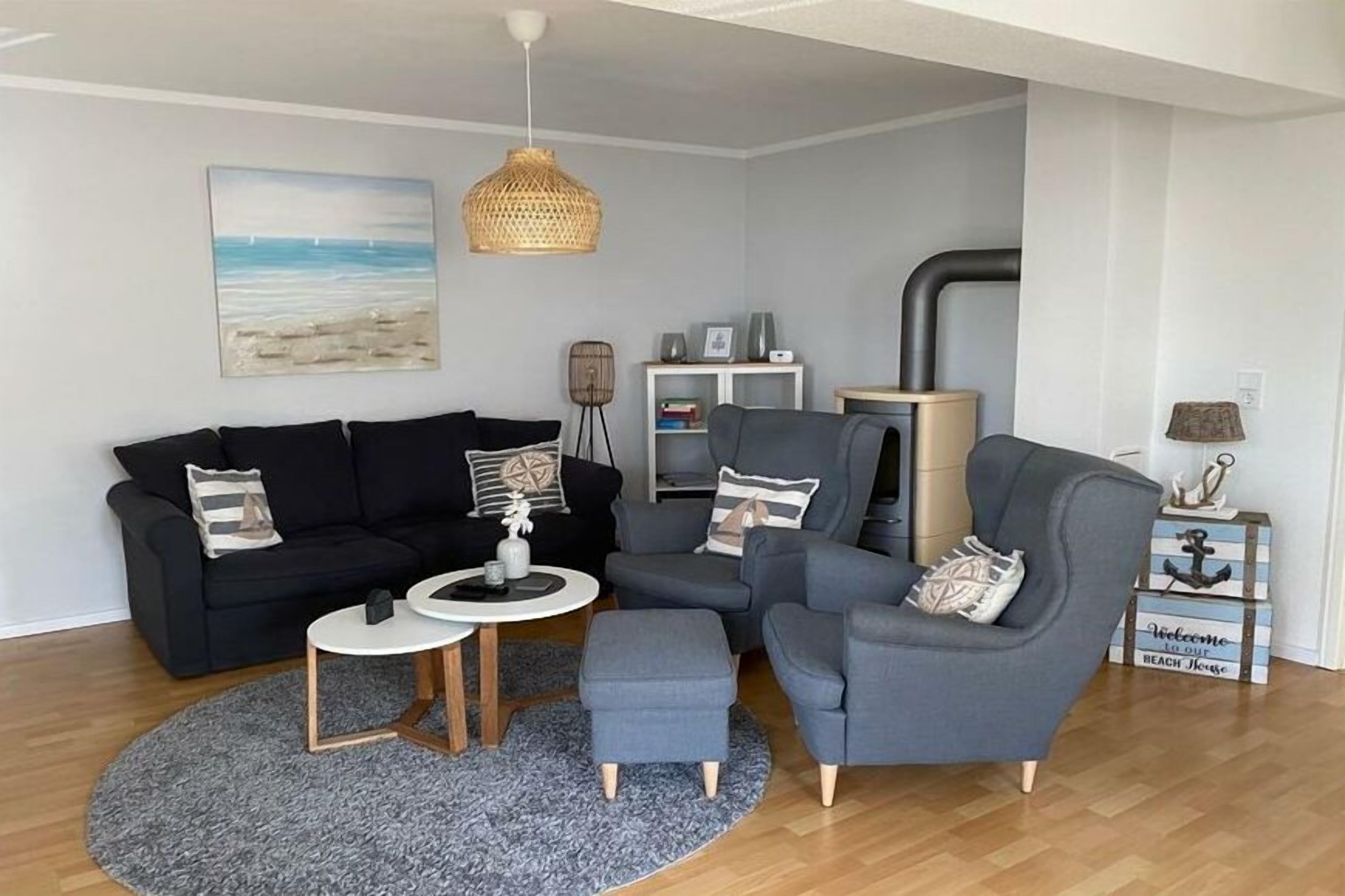 Ein Wohnzimmer mit einem schwarzen Sofa, einem grauen Sessel, einem runden Couchtisch und einem kleinen Beistelltisch.