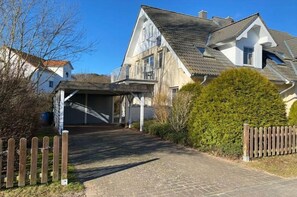 Ein Wohnhaus mit befestigter Auffahrt, Holzzaun und gepflegtem Rasen.