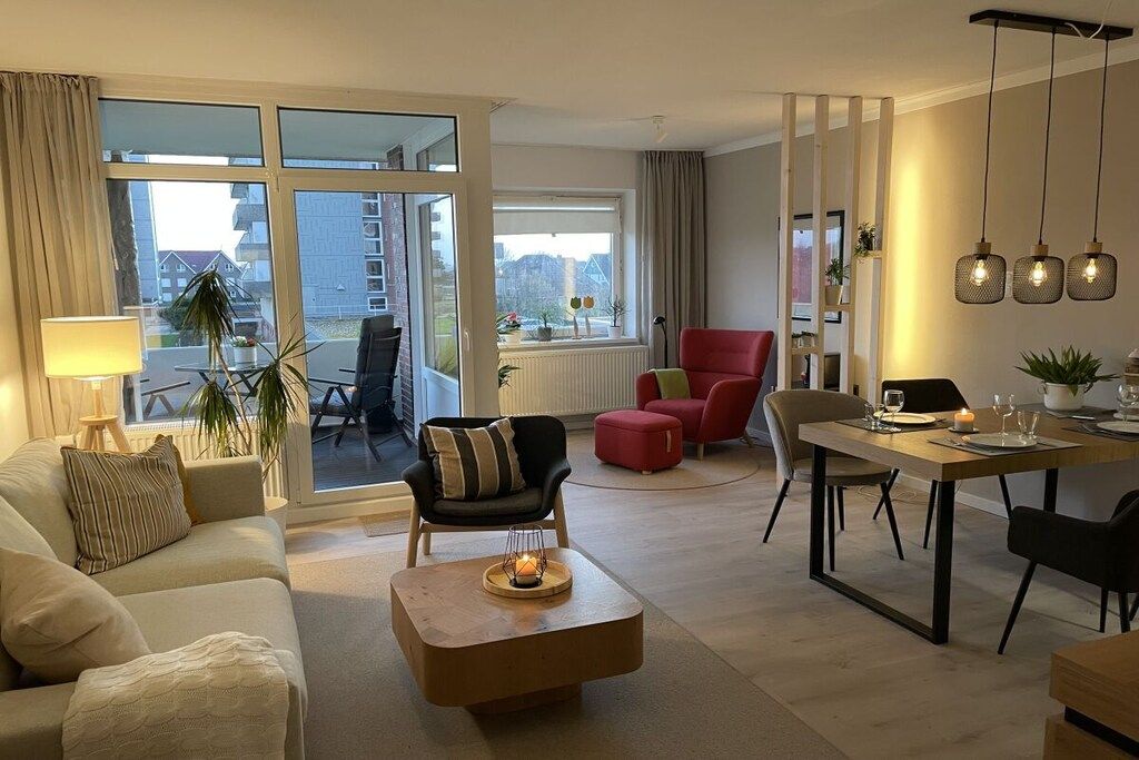Una sala de estar moderna con sofá, sillón, mesa de comedor y vistas a través de amplios ventanales.