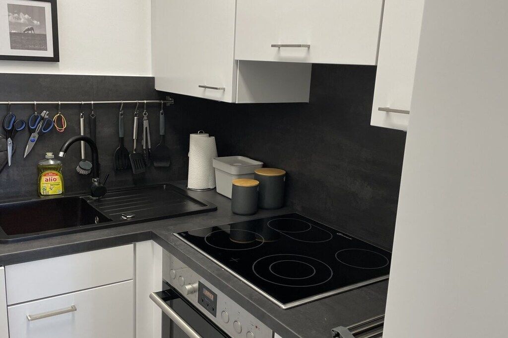 A modern kitchen with a black countertop, stainless steel appliances, and white cabinets.