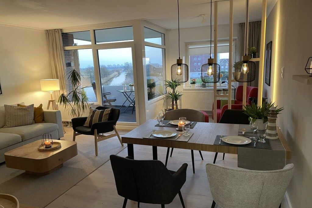 Un salon moderne avec un coin repas, de grandes fenêtres et une vue sur l’extérieur.