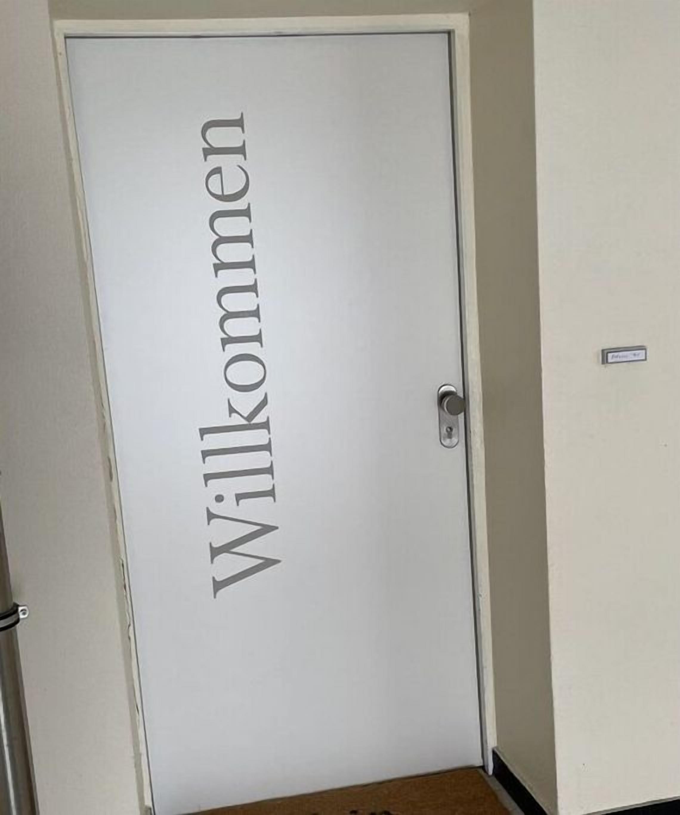 Uma porta com a inscrição 'Willkommen', indicando uma placa de boas-vindas.