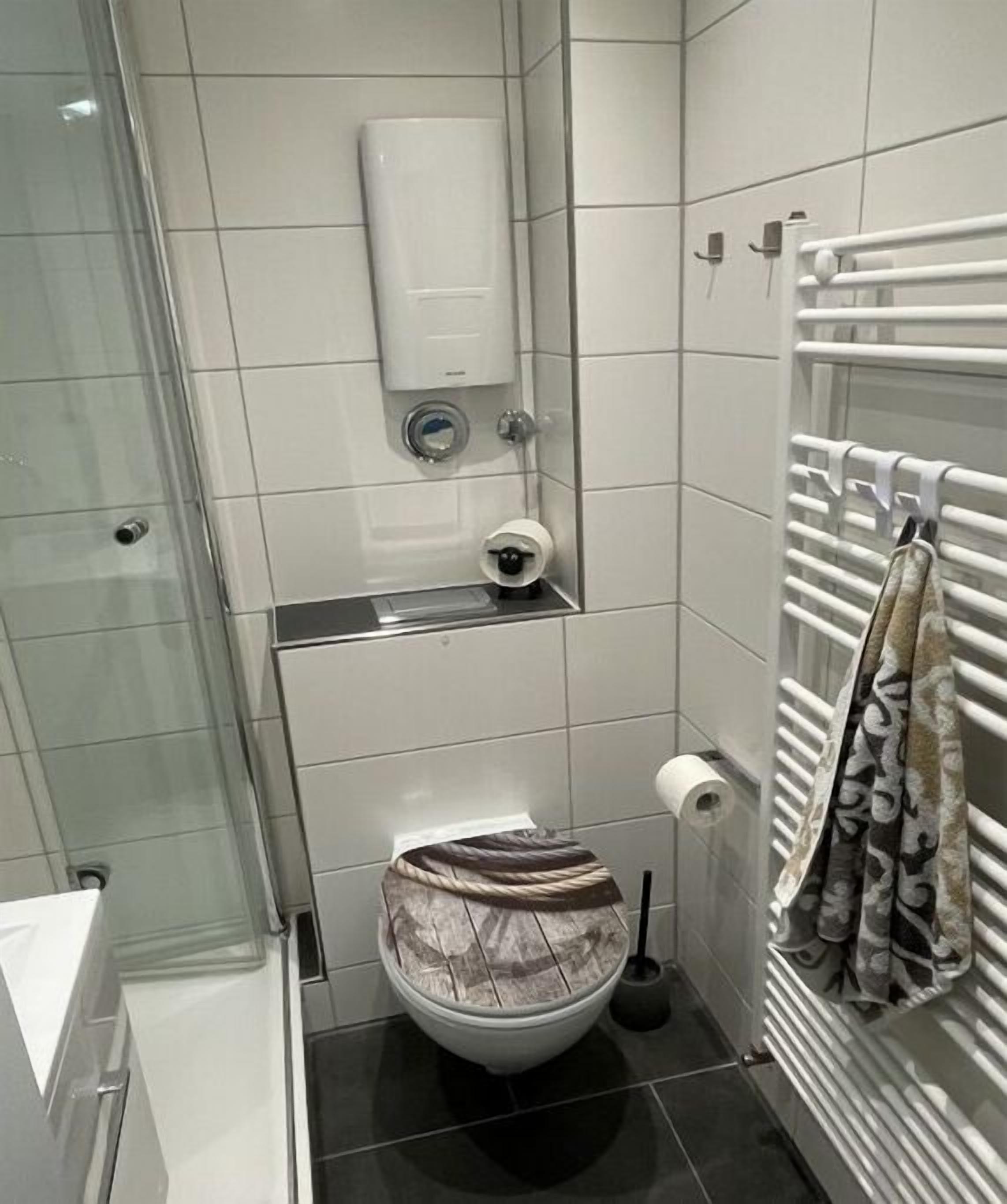 A bathroom with a toilet, bidet, hand dryer, and a glass shower enclosure.
