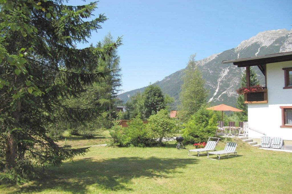 A residential property with a lawn, outdoor seating, and a mountain backdrop.