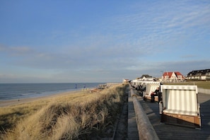 Ein Promenadweg am Strand mit Strandkörben und Häusern im Hintergrund.