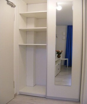 A white closet with multiple shelves and a mirror. - Holiday apartment with 1 bedroom (Breege\/Juliusruh OT Juliusruh)