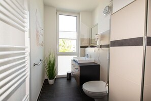 Ein modernes Badezimmer mit Toilette, Waschbecken und Spiegel.