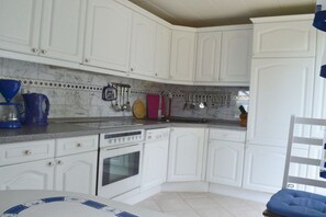A kitchen with white cabinets, a stove, and a sink. - Holiday home with 2 bedrooms (Plau am See)