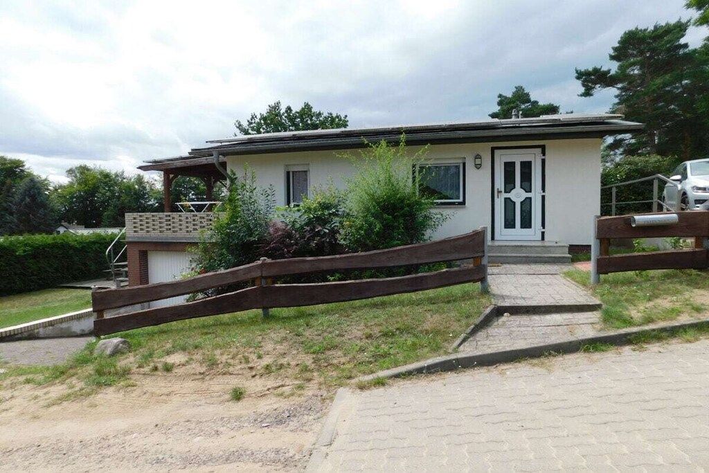 A single-story building with a front entrance, a small porch, and a wooden fence.