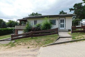 A single-story building with a front entrance, a small porch, and a wooden fence. - Holiday home with 2 bedrooms (Plau am See)