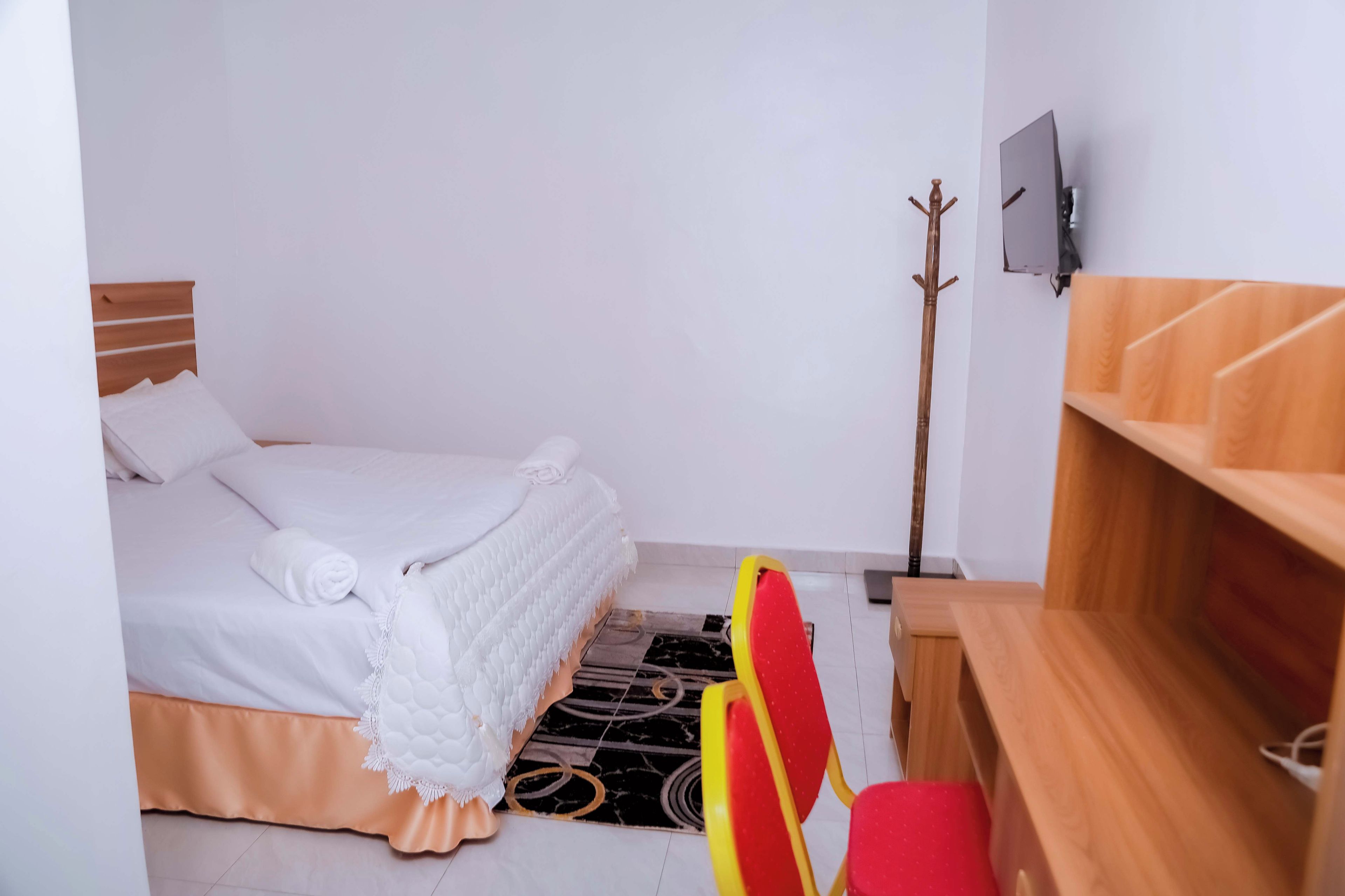 Una habitación pequeña y ordenada con una cama, un escritorio y una silla.